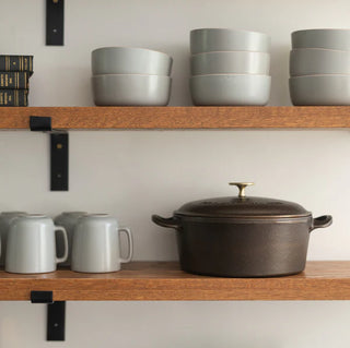 Lancaster 5 Quart Dutch Oven Cast Iron with Brass Knob highlighting its durable double-handle grip for safe lifting and serving.